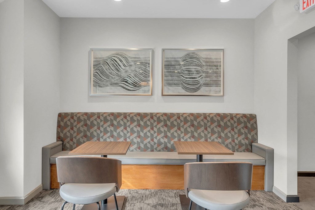 a dining area with two tables and chairs and two paintings on the wall