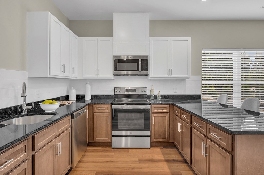 a kitchen with white cabinets and black counter tops and a stainless steel stove