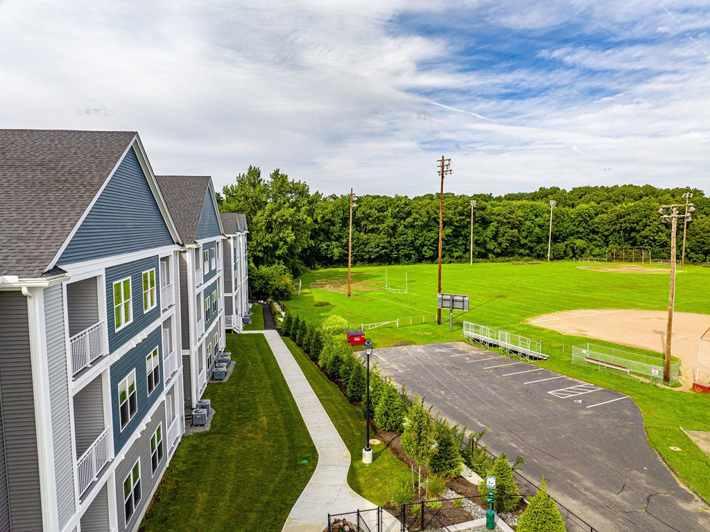 a view of a parking lot with houses and a baseball field