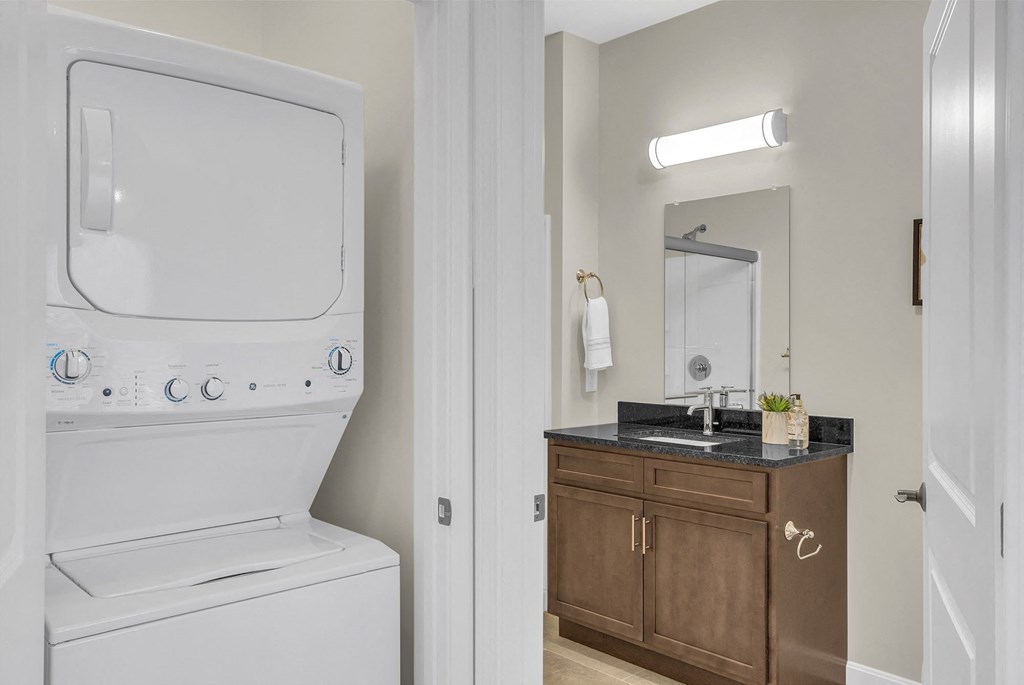 a bathroom with a washer and dryer next to a sink and a mirror