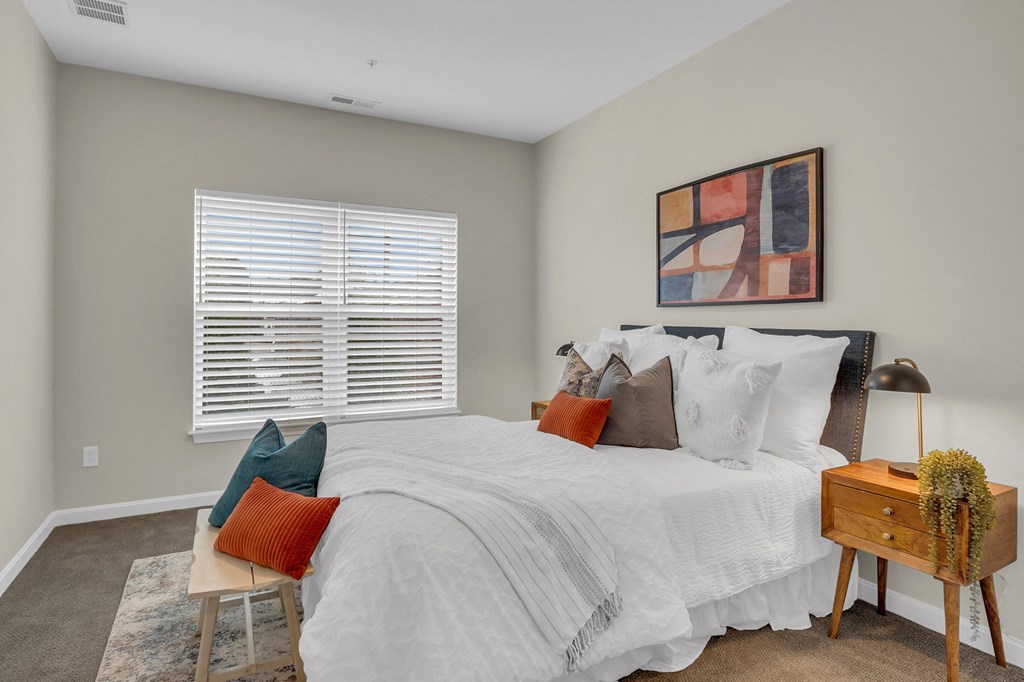 bedroom with white bedding and pillows and a window