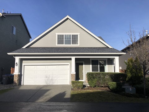 A house with a grey roof and a white garage door.