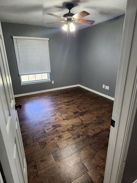 a empty room with wood floors and a ceiling fan