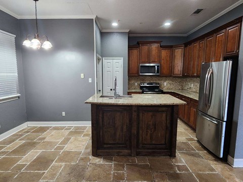 a kitchen with a center island and a stainless steel refrigerator