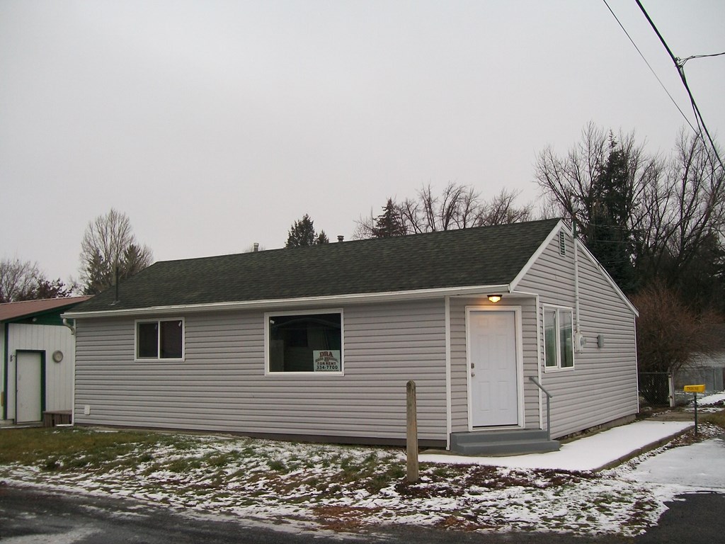 A small house with a grey roof and a white door.