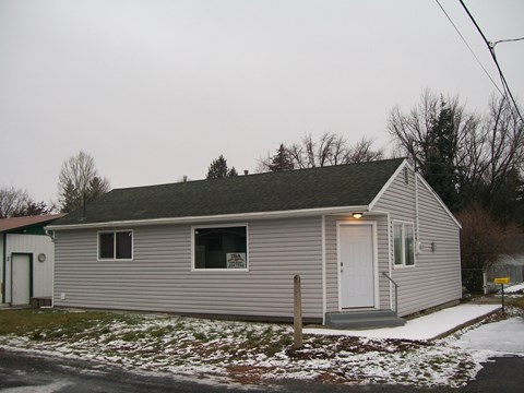 A small house with a grey roof and a white door.