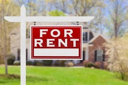 A red and white for rent sign in front of a house.