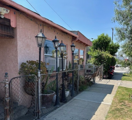 A pink building with a metal fence and lamp posts.