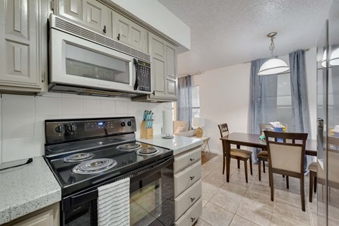 a kitchen with a stove and microwave and a dining room table