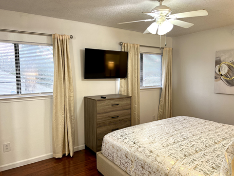 a bedroom with a bed and a ceiling fan and a tv
