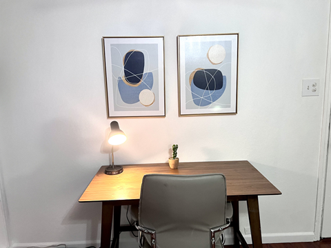 a desk with a chair and two paintings on the wall