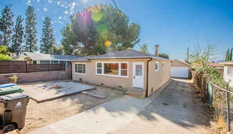 a small tan house with a yard and a fence