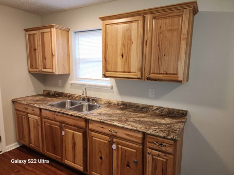 A kitchen with wooden cabinets and a marble countertop.
