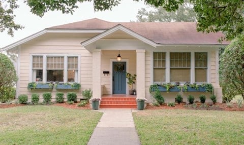 A small house with a red front door and two windows with flower boxes.