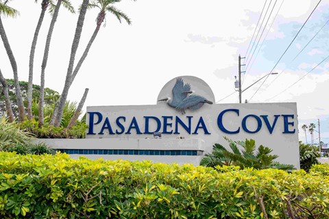 A sign for Pasadena Cove is displayed in front of some green shrubbery.