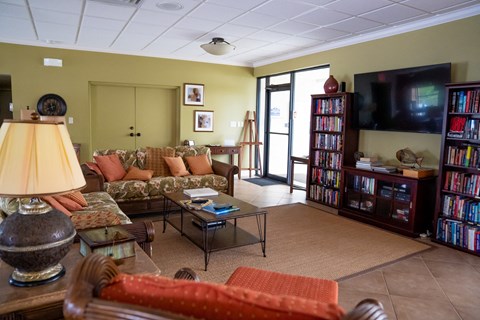 A living room with a couch, a coffee table, a lamp, and a bookshelf.