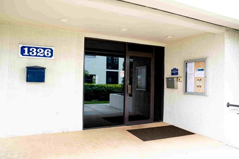 The image shows the entrance to a building with a glass door and a sign that reads "1326".