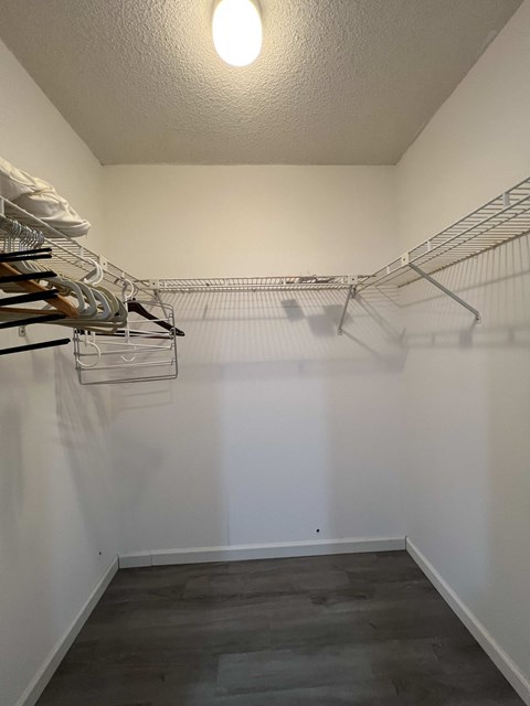 A walk in closet with clothes hanging on racks.