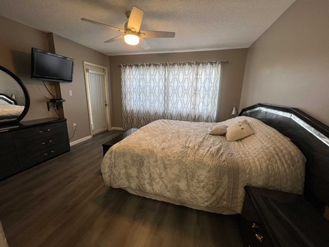 A bedroom with a bed, dresser, and television.