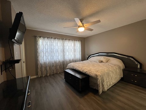 A bedroom with a bed, dresser, and television.