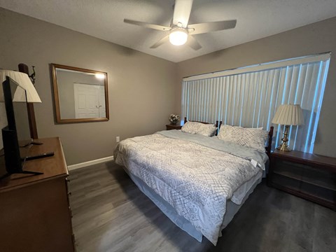 A bedroom with a bed, dresser, and window with blinds.