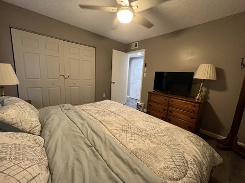 A bedroom with two beds, a dresser, and a ceiling fan.