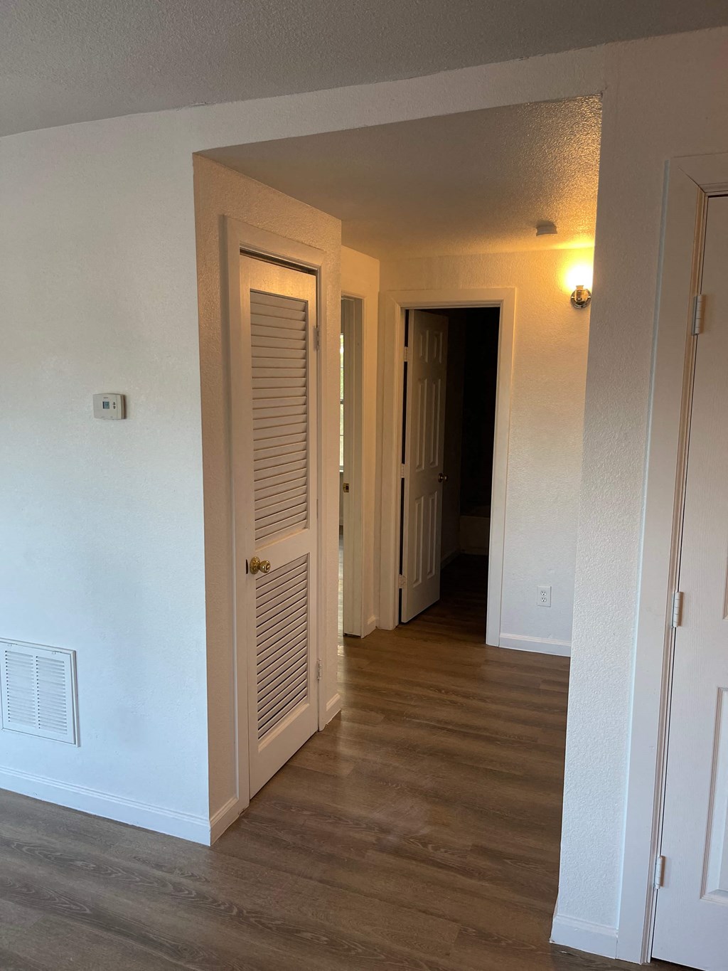 a hallway with an open door and a door to a closet