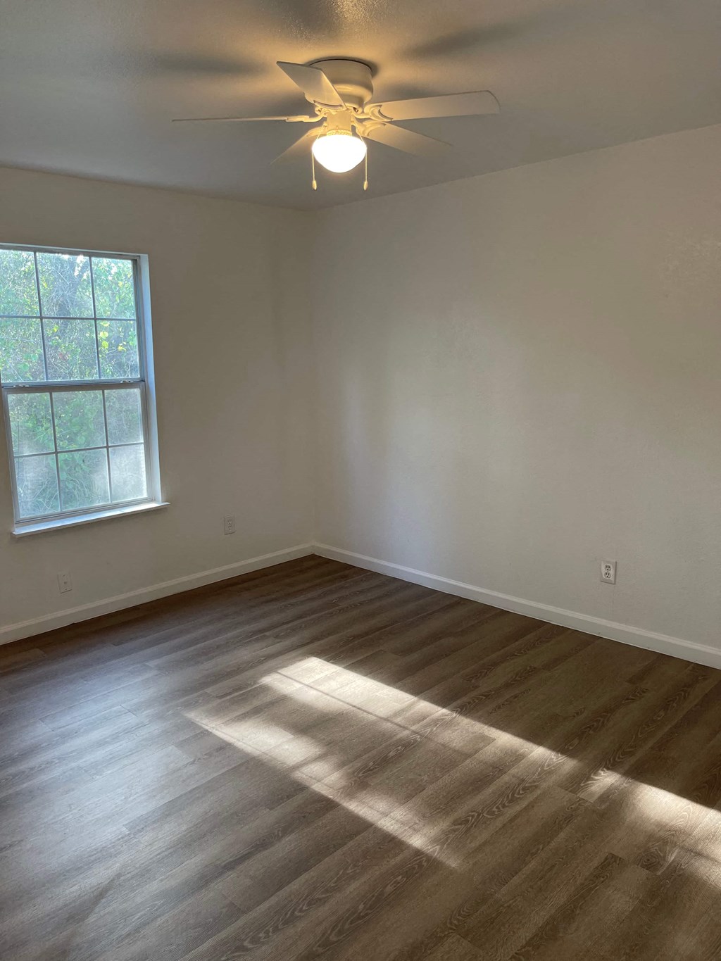 an empty room with a ceiling fan and a window