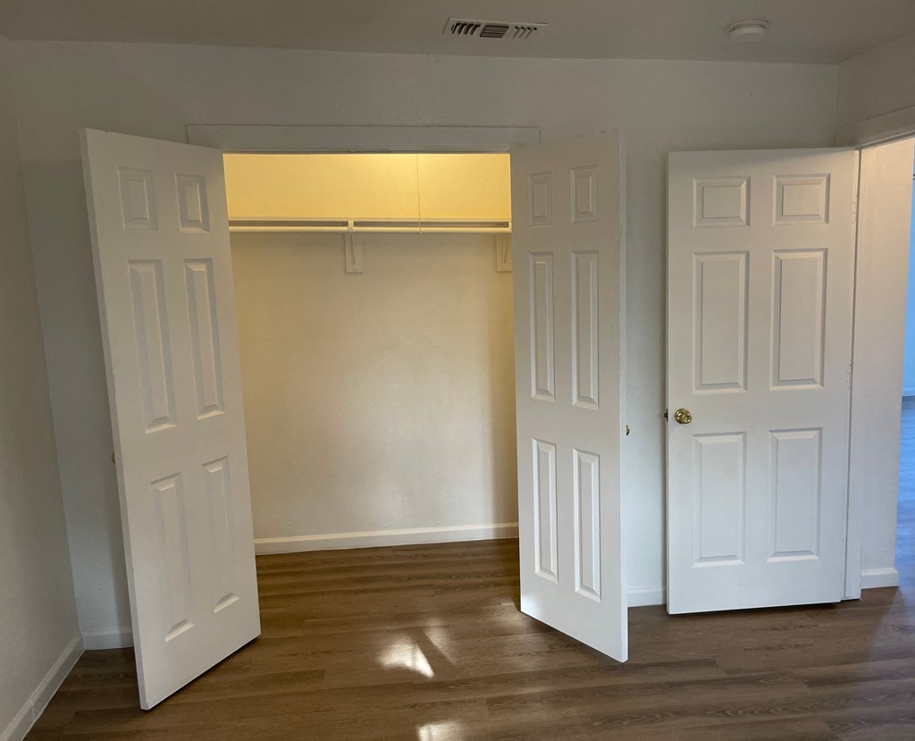 an empty bedroom with two doors and a closet