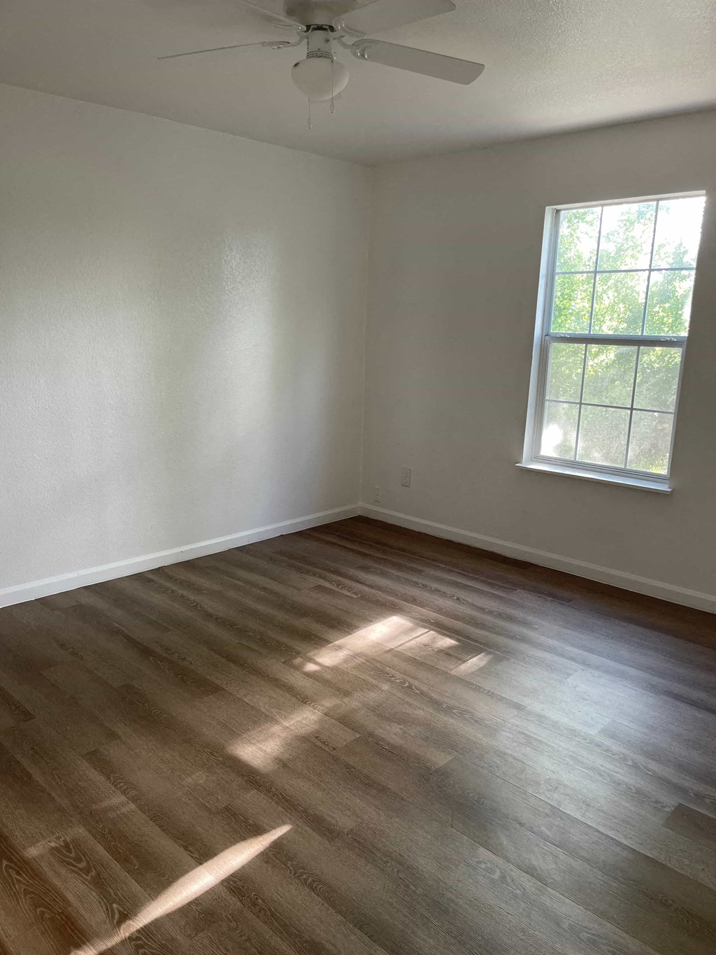 an empty room with wooden floors and a window
