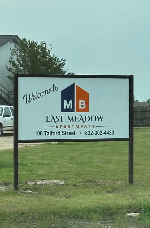 A sign welcoming people to East Meadow Apartments.