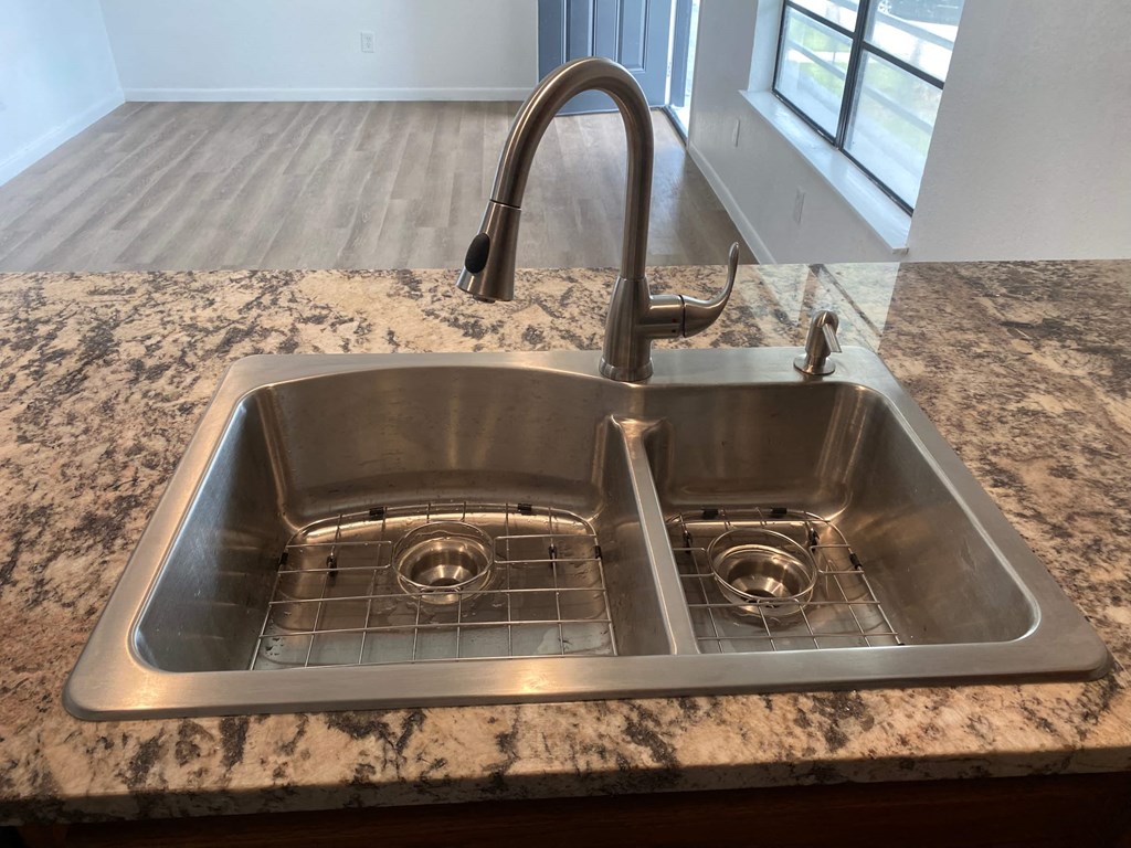 a kitchen with a stainless steel sink and a granite counter top