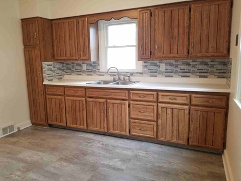 an empty kitchen with wooden cabinets and a sink