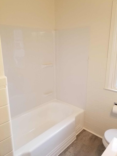 a white bathroom with a tub and a toilet