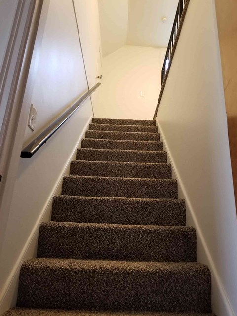 a flight of stairs with carpeted stairs leading up to a white wall and stairs
