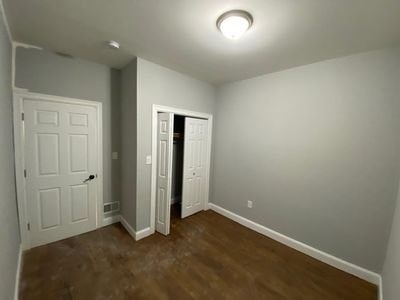 A room with a white door and a brown floor.
