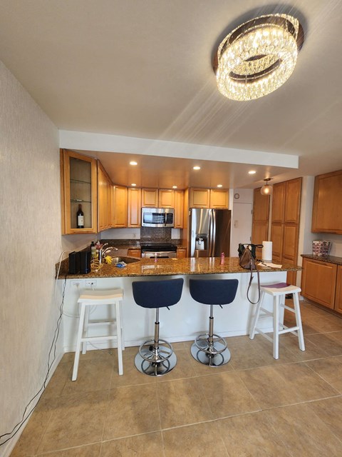 A kitchen with a bar area and a chandelier hanging from the ceiling.