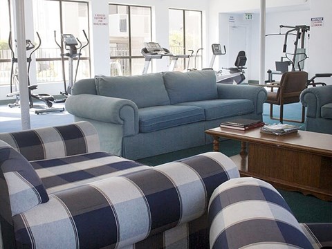a living room with blue and white furniture and a gym in the background