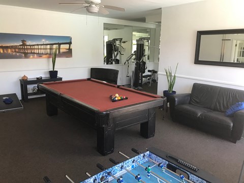 a red pool table in a living room with a black couch