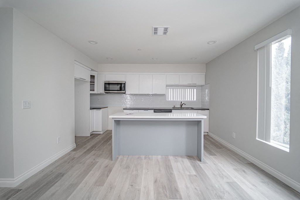 an empty kitchen with white cabinets and a white counter top