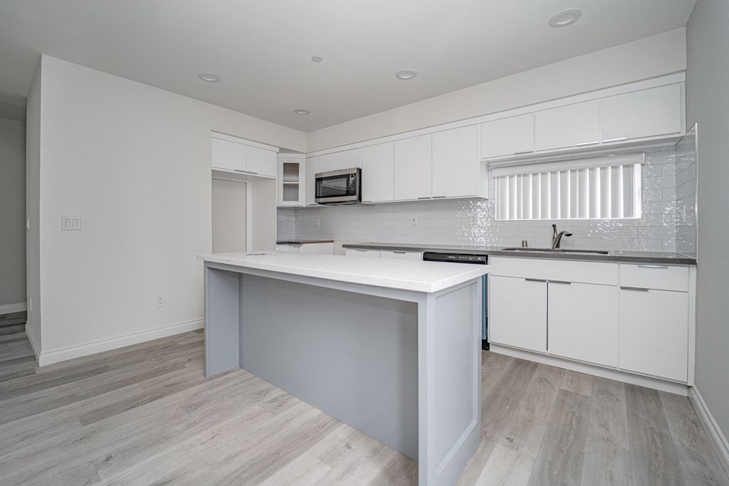 an empty kitchen with white cabinets and a white counter top