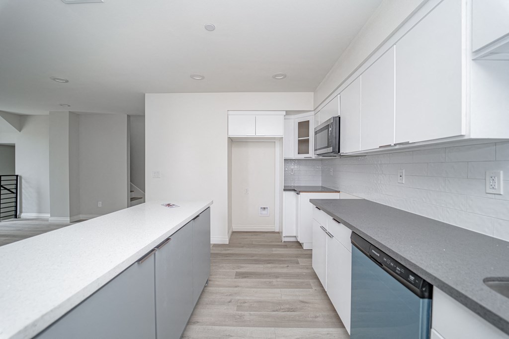 an empty kitchen with white counter tops and white cabinets