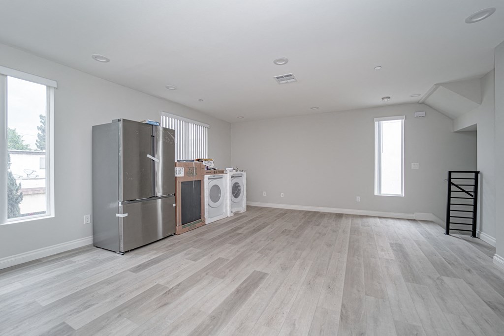 an empty living room with a refrigerator and a washer and dryer in it