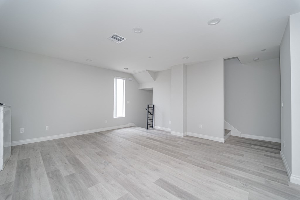 an empty living room with white walls and wood flooring