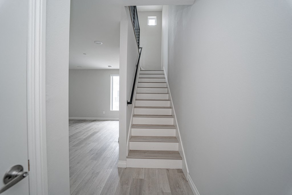 a staircase in a home with white walls and wood floors