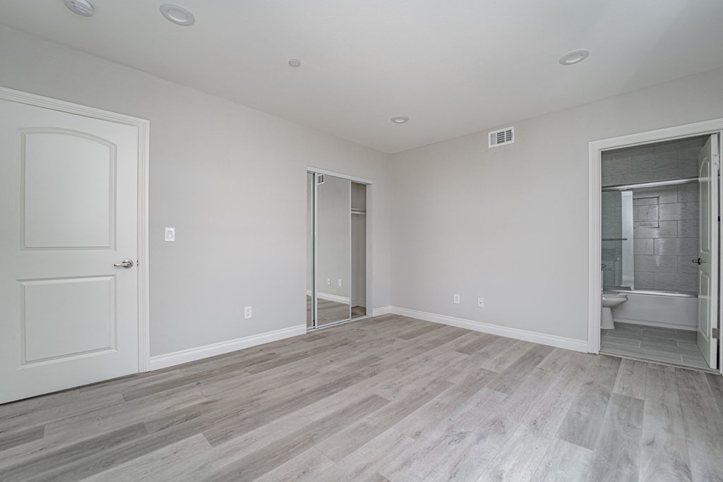 an empty bedroom with a door to a bathroom and a closet