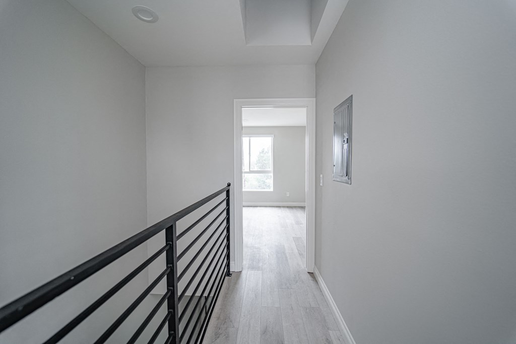 an empty hallway in a home with a staircase and a window