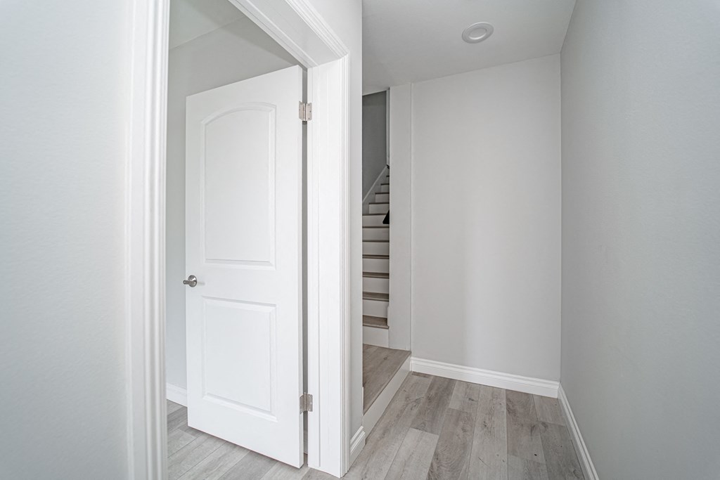 a small room with a white door and a staircase in it