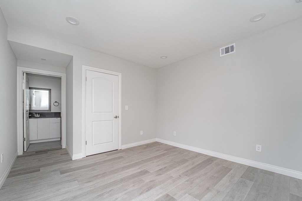 an empty living room with a door to a kitchen