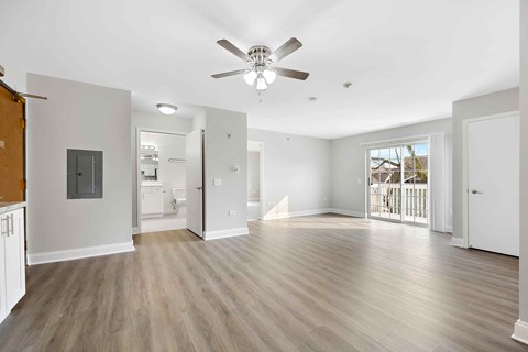 A spacious room with a ceiling fan and light fixture, and a wooden floor.